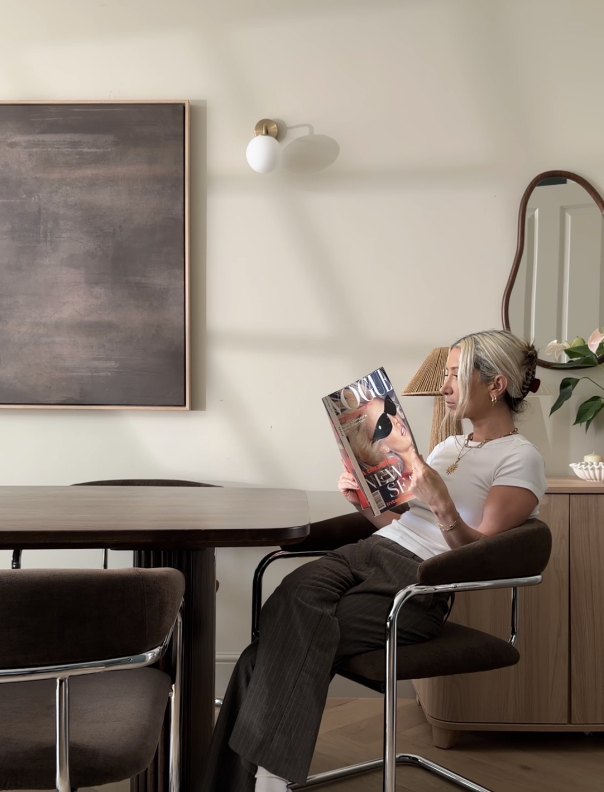 Amelia reading a magazine in a velvet dining chair at home