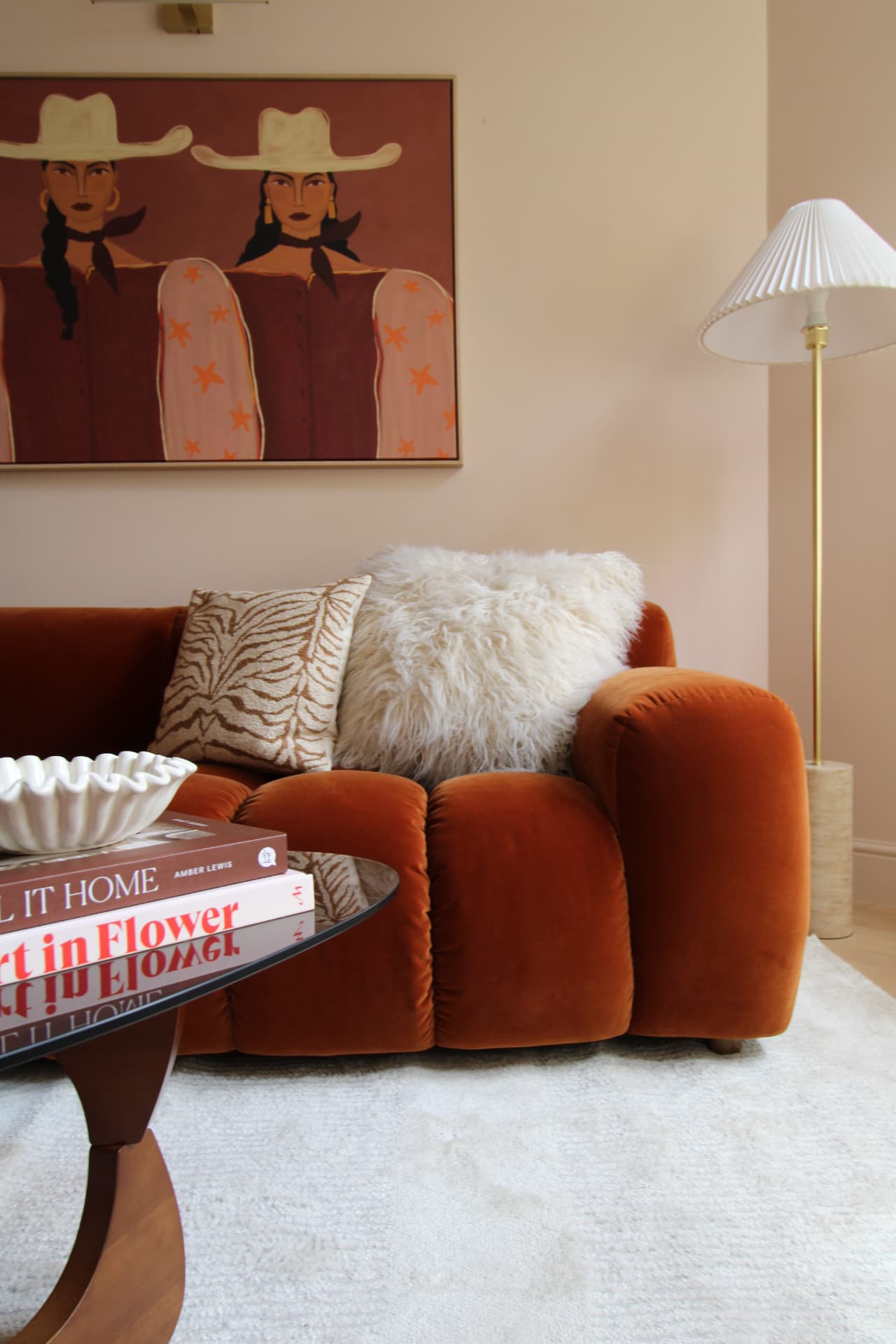 Rust velvet sofa, cowgirl print and a pleated lamp in a pink living room